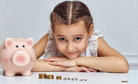 Little Girl With A Piggy Bank And Some Coins