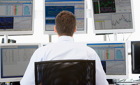 Man Sitting In Front Of Multiple Monitor Screens