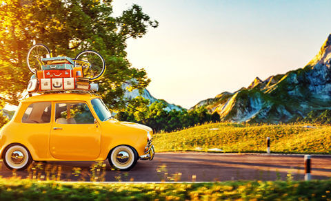 Yellow Car With Travel Gear Including A Bicycle Loaded On The Roof