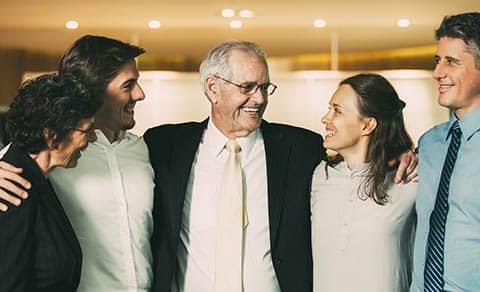 Smiling Senior Business Leader Embracing Coworkers