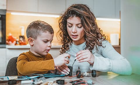 Mother and son sitting at the table working on a science project