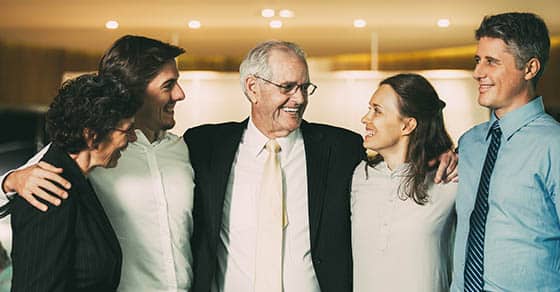 Smiling Senior Business Leader Embracing Coworkers