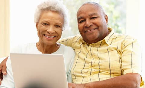 Elderly man and woman sitting on a couch with a laptop