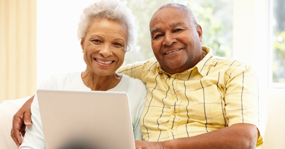 Elderly man and woman sitting on a couch with a laptop