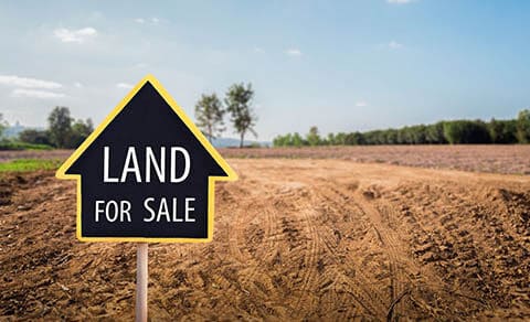 Land,for,sale,sign,against,trimmed,lawn,background.,empty,dry