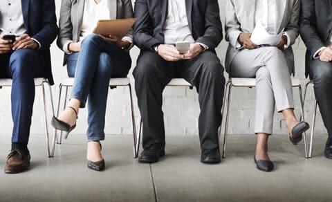 job applicants sitting in a row of chairs only visible from the waist down