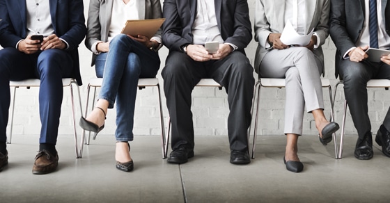 job applicants sitting in a row of chairs only visible from the waist down