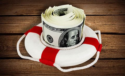 Roll of money inside a Life-saving ring on a wooden background