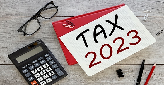 Desktop with calculator, reading glasses, pens and notepaper that says Tax 2023