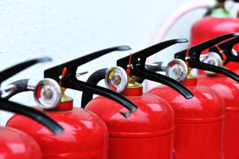 Close up of bright red fire extinguishers in a row