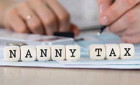 Photo of hands filling out a form with blocks spelling NANNY TAX