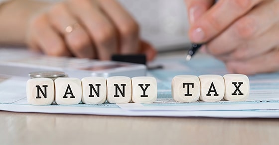 Photo of hands filling out a form with blocks spelling NANNY TAX