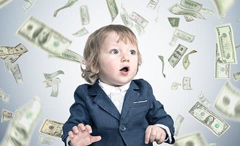 A, young, child, in, a, suit, looks, surprised, as, dollar, bills, rain, down, around, them, symbolizing, wealth, or, unexpected, financial, gains.