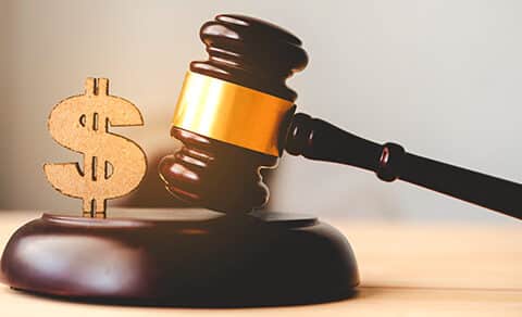 The, image, shows, a, judge's, gavel, next, to, a, gold, dollar, sign, symbolizing, the, financial, implications, of, legal, decisions, such, as, lawsuit, settlements, or, court, awards.