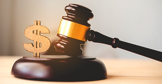 The, image, shows, a, judge's, gavel, next, to, a, gold, dollar, sign, symbolizing, the, financial, implications, of, legal, decisions, such, as, lawsuit, settlements, or, court, awards.