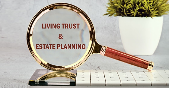 A, magnifying, glass, highlighting, the, words, "Living, Trust, &, Estate, Planning", placed, over, a, calculator, with, a, small, potted, plant, in, the, background, symbolizing, financial, planning, and, attention, to, detail.