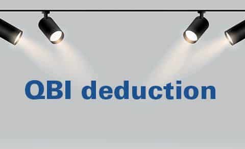 Four, black, spotlights, shine, down, on, the, bold, blue, text, “QBI, deduction”, against, a, light, gray, background, emphasizing, its, importance.
