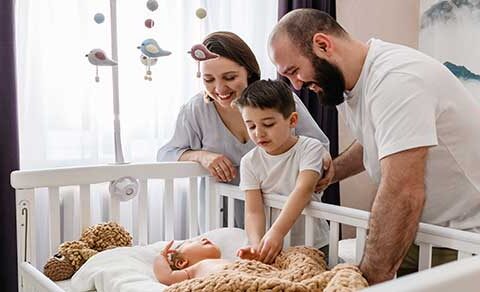 Family, parents, siblings, newborn, crib, nursery, warmth, love, tenderness, happiness, cozy, gentle, bonding,