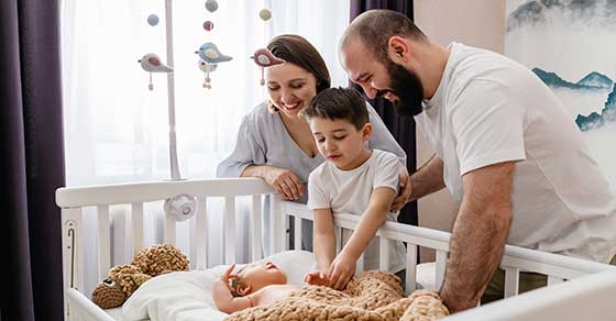 Family, parents, siblings, newborn, crib, nursery, warmth, love, tenderness, happiness, cozy, gentle, bonding,